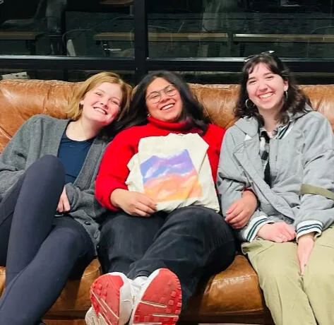 Three friends on a leather couch at Kairos