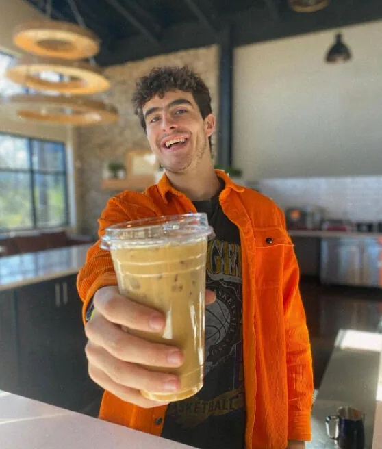 A guest holding an iced drink at Kairos Coffeehouse
