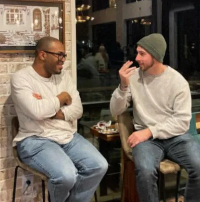 Two friends talking on stools at Kairos
