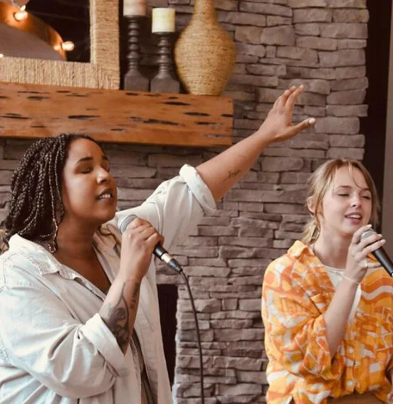 Two young adults singing during worship at Kairos