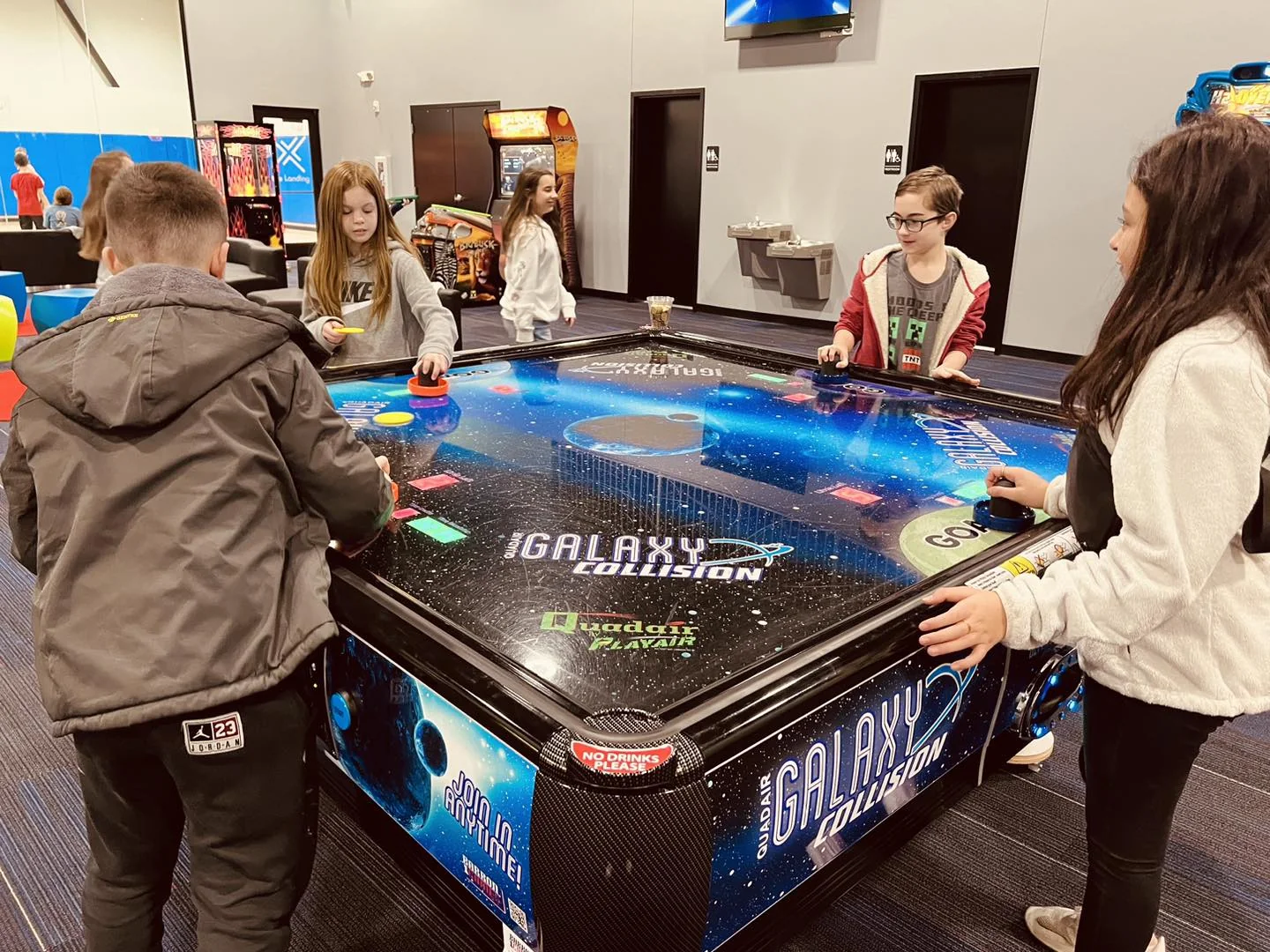 A group crowded around the air hockey table